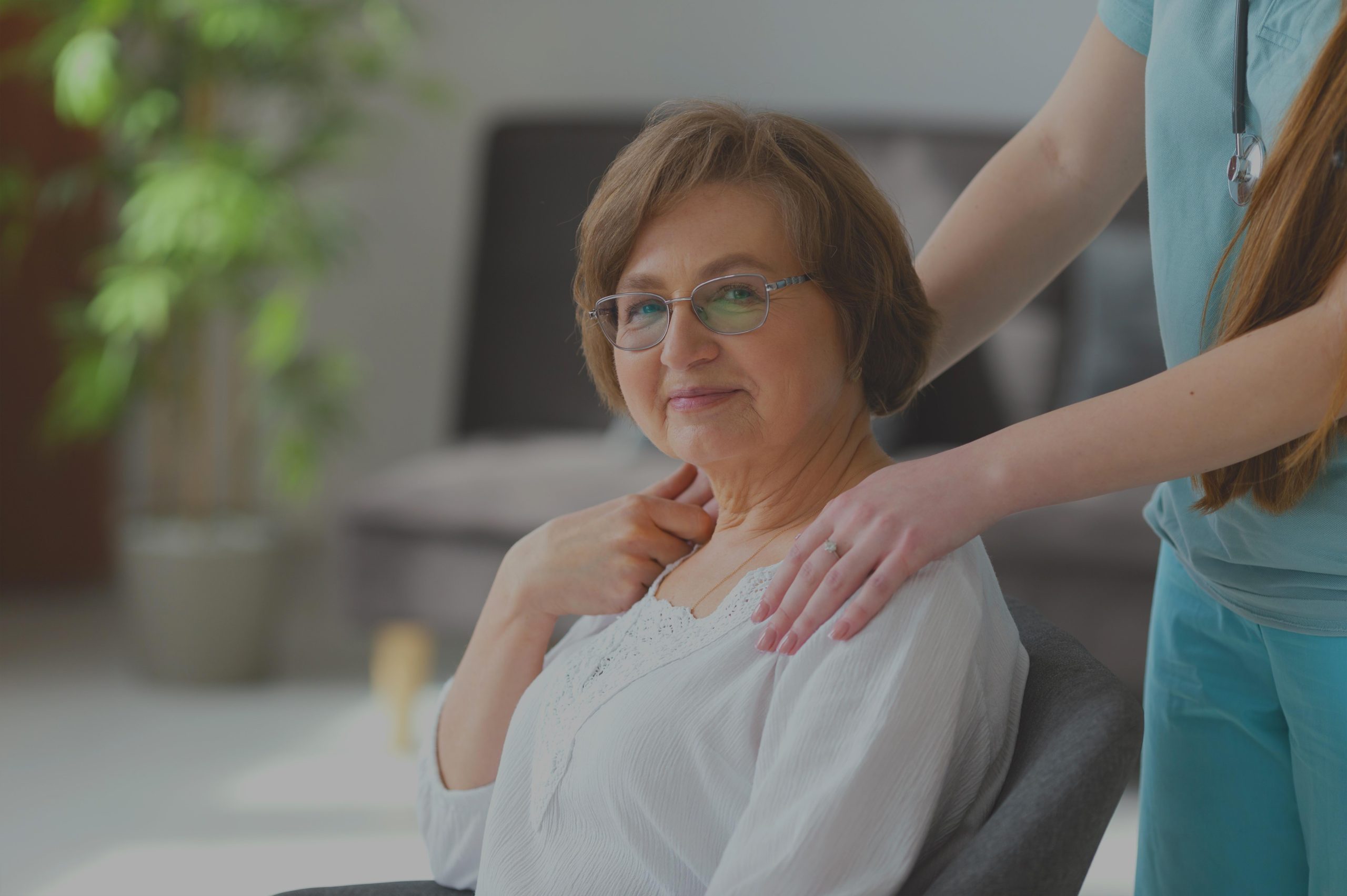 close up of older woman posing in a chair with a home health and hospice care nurse next to her